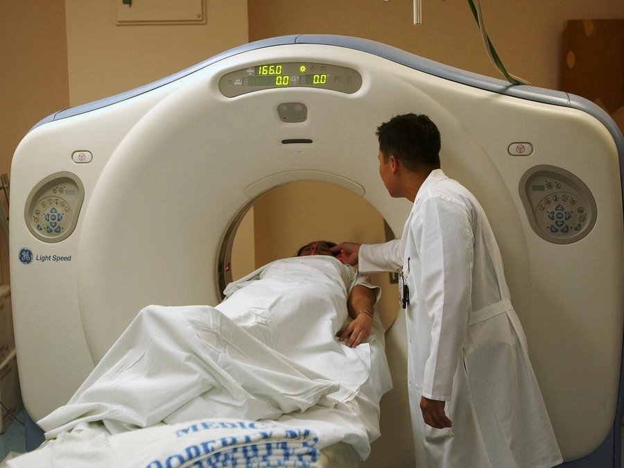 Patient undergoing a CT scan with a doctor assisting